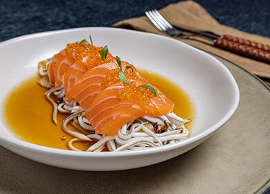 Salmón noruego fresco en láminas sobre gulas salteadas en ajo y guindilla, en caldo corto de setas